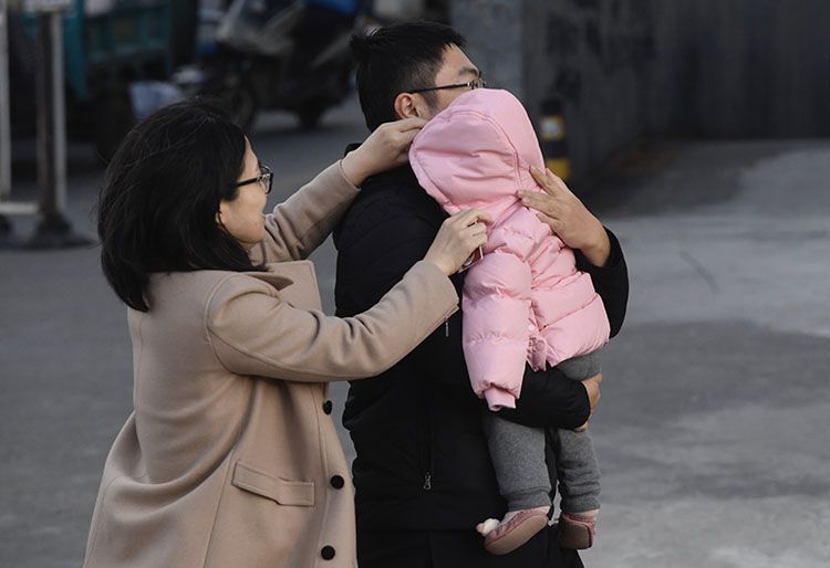 广渠路,寒风中家长给孩子戴好帽子。