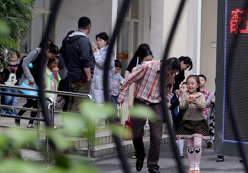 资料图片:2015年5月9日,在上海市一民办小学门口,小朋友和家长参加完招生面谈,走出学校。新华社记者 刘颖 摄
