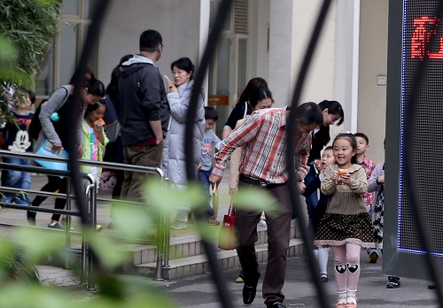 资料图片：2015年5月9日，在上海市一民办小学门口，小朋友和家长参加完招生面谈，走出学校。新华社记者 刘颖 摄