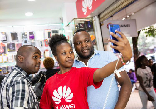 4月27日，在肯尼亚首都内罗毕市中心，一名华为手机店员向顾客展示自拍功能。（新华社）
