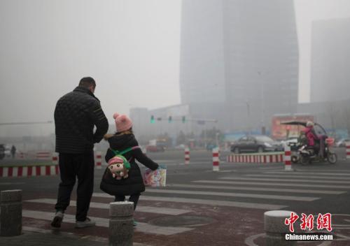 资料图：北京市民在雾霾中出行。中新社记者 刘关关 摄