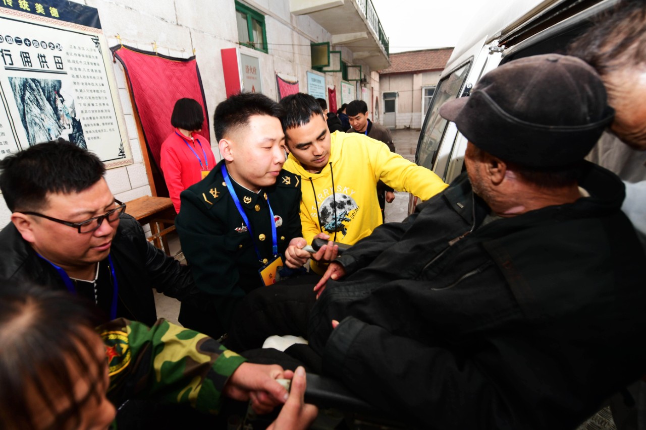 ▲吴景硕与志愿者将患病的老人合力抬上救护车