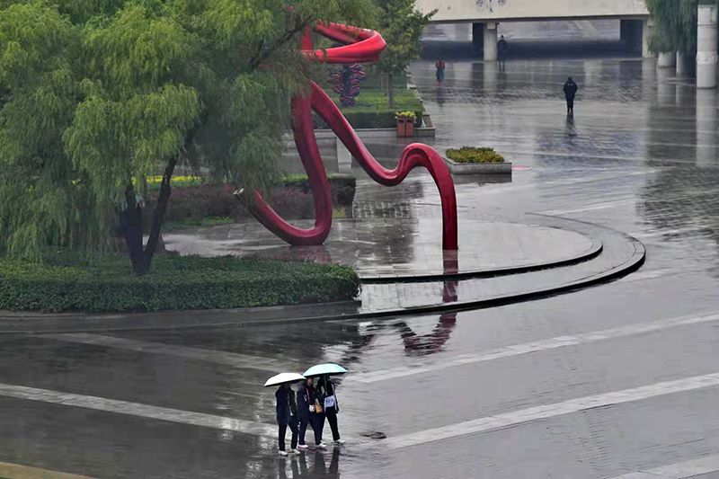 奥体中心，行人在撑伞前行。