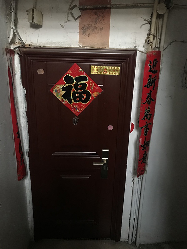 一旁邻居家的朱红色大门，张贴了关公画像、佛咒。