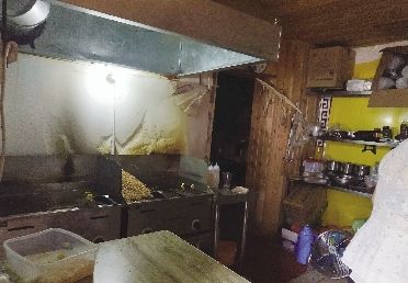 長江商報記者拍到的武漢東湖路附近的“梁小猴鐵板炒飯”后廚，紙糊的墻壁油跡斑斑，一大堆米飯已提前炒好。本報記者 金慧 攝