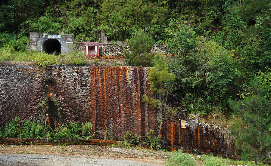 9月9日，内苗铅锌矿，矿洞口强酸水从矿洞流出后，一部分顺着水泥和石头砌的墙体流下来，把墙面染成了铁锈色。