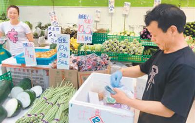 香港湾仔的菜市场只收现金，摊主闲下来整理花花绿绿的港币。本报记者 连锦添摄