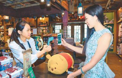 香港迪士尼乐园度假区日前与微信支付达成企业联盟合作，游客从即日起在香港迪士尼乐园可以使用微信支付。图为游客体验用微信支付购买纪念品。新华社记者 秦晴摄