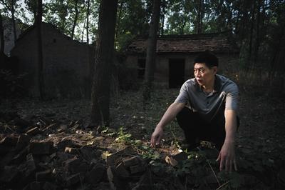 6月27日，河南商丘夏邑县，张玉玺蹲在老宅的废墟前。当年事发后，张玉玺的家被砸，仅剩堂屋（图中背景屋），被当作陈尸地。