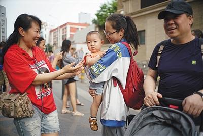 2018年6月8日，北京市朝阳区陈经纶中学，一名刚结束高考的考生抱着前来迎接她的弟弟。新京报记者 薛珺 摄