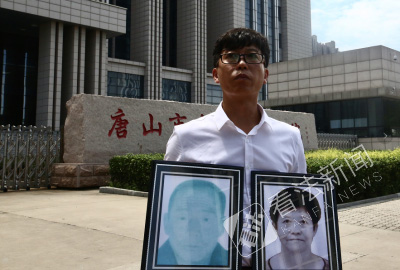 在法院门口，廖海军手捧父母遗像 摄/记者 杨小嘉
