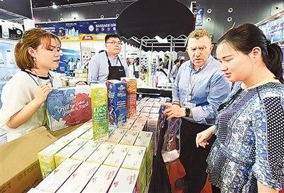 2018中国义乌进口商品博览会上，一位新西兰客商向中国顾客推销奶制品。龚献明摄（人民视觉）