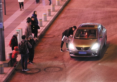  2月15日晚，西单一些乘客站在马路上等车，一辆“黑车”司机正在和乘客“讨价还价”。