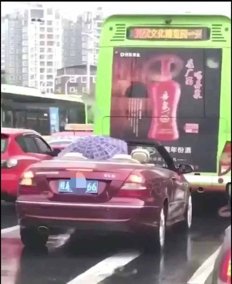 男子打雨伞开敞篷跑车 网友：土豪的烦恼你不懂