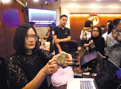 5月22日,庭审后王女士在法庭上向记者展示快递员用于砸击王女士头部的石块。新京报记者 王贵彬 摄