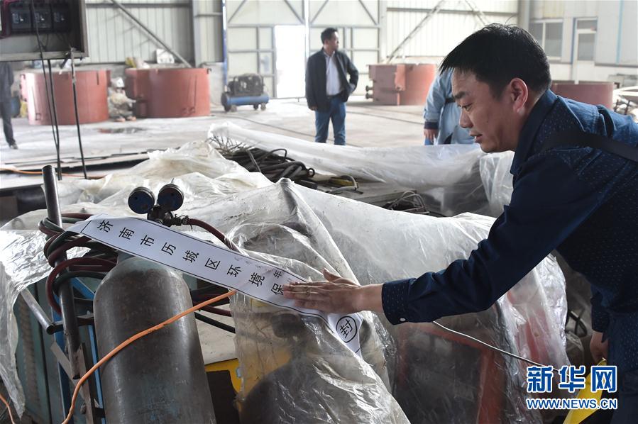 4月17日，一名济南市环保局的工作人员在查封设备 图片来源：新华社