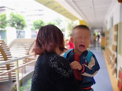  眉山一幼儿园内，被家人抱着哭泣的小男孩。