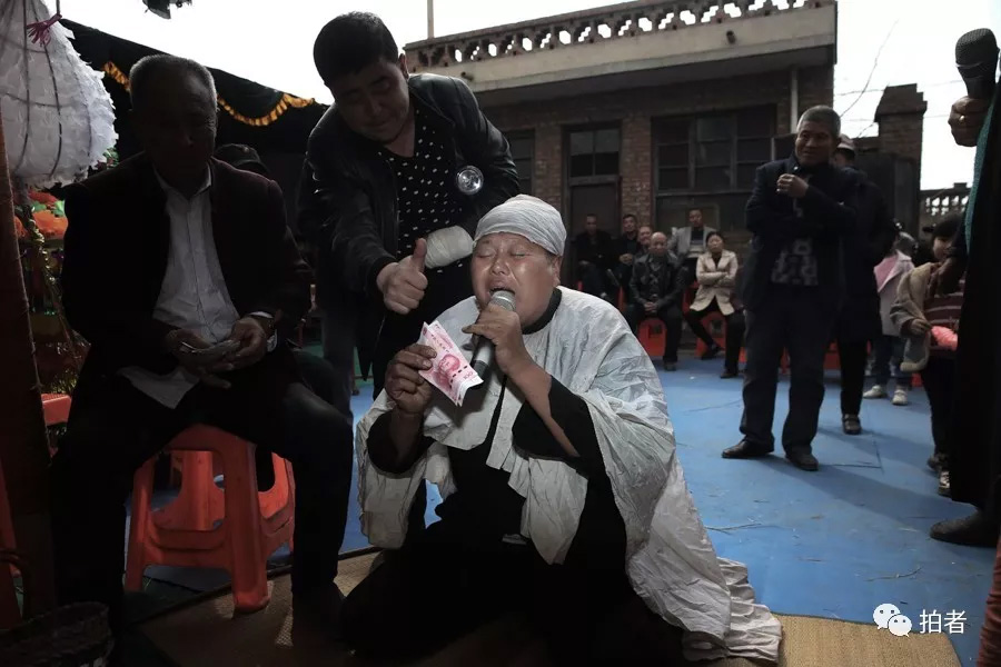 △ 三平跪在灵前哭唱,主家送上赏钱后对其伸出大拇指表示称赞。