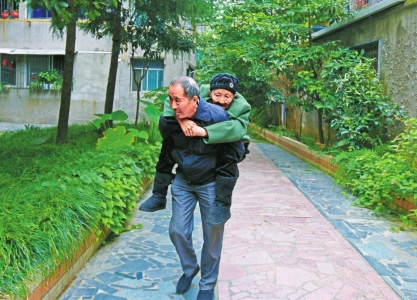 吴国元背着92岁的母亲下楼散步。本文图片 华西都市报