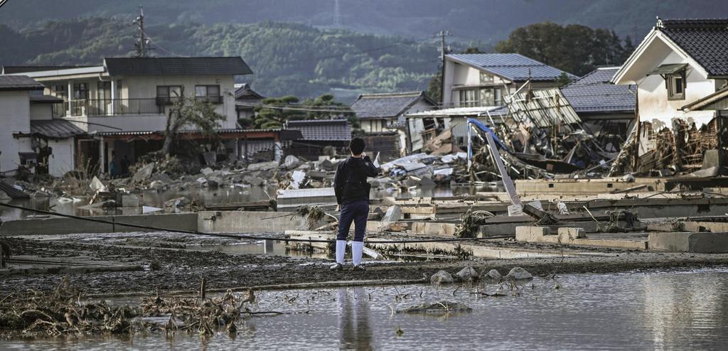  日本灾民站在因河川溃堤而遭受洪灾的住宅区前（《产经新闻》）