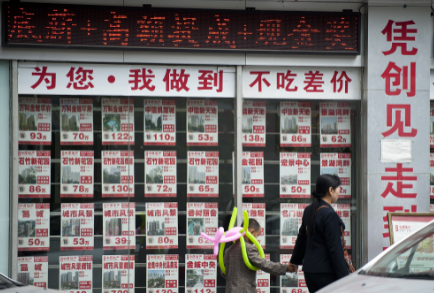 某房产中介公司在店面窗户上贴满了密密麻麻的房源信息。视觉中国