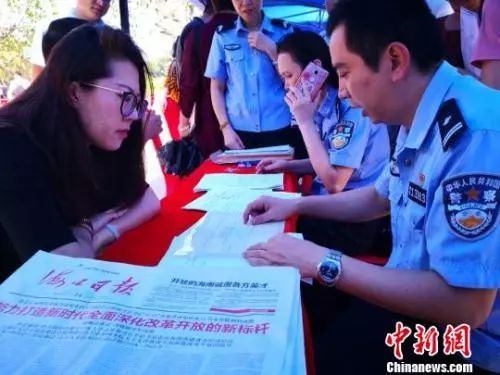 资料图：2018年5月14日，海口公安民警在海口市三角池公园为民众办理落户手续、提供落户咨询服务。　尹海明 摄