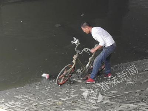 一名工作人员正在打捞共享单车 摄/记者 董振杰