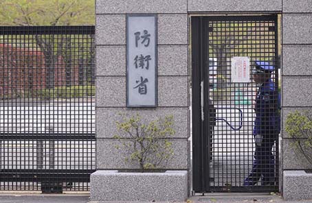 资料图：2013年4月9日，在日本东京的防卫省总部，一名工作人员在大门旁守卫。新华社发