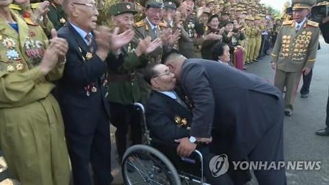 今年7月,金正恩俯身与参加老兵大会的金铁万交谈。(韩联社)