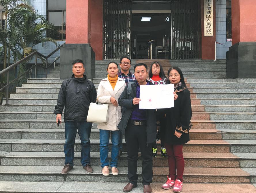 昨日,该案宣判后,几名被拐幼儿的家长拿着判决书在法院门口合影。 受访者供图