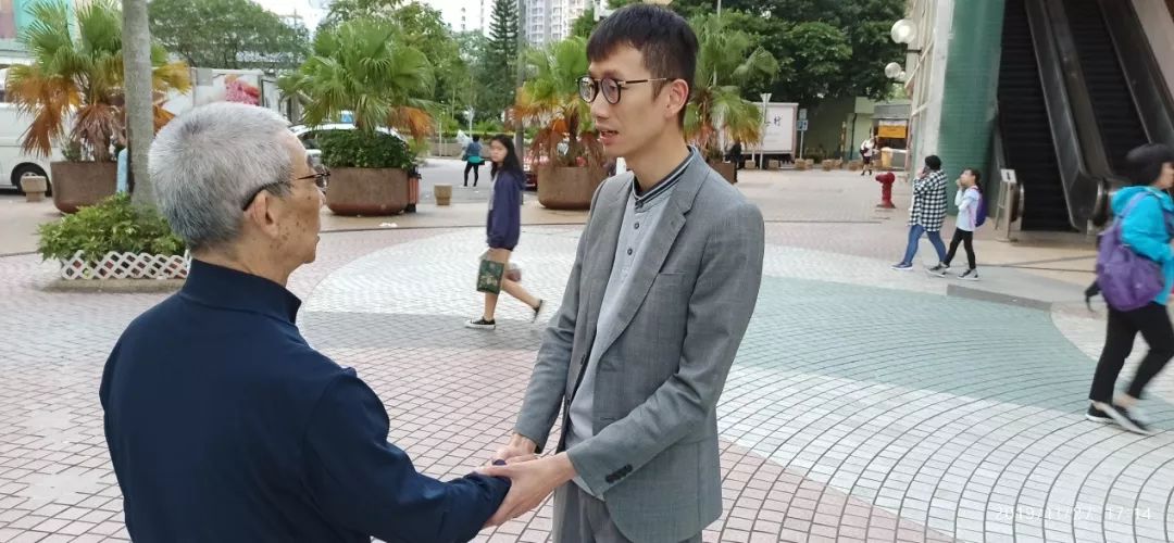 陈志豪(右)与一位老人握手。