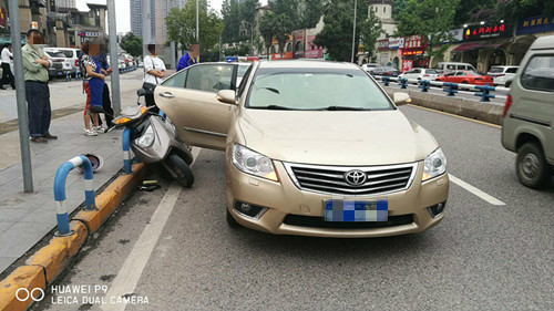 轿车随意突开车门 扇倒过路摩托车