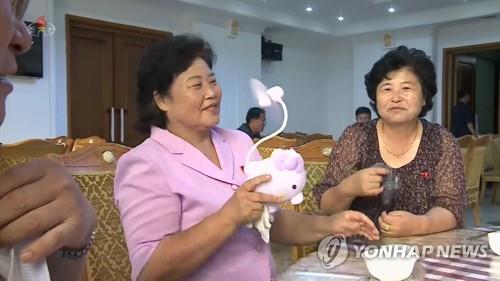朝鮮中央電視臺26日播出的“三伏天狗肉湯”的介紹節目中,鏡頭捕捉到一位中年婦女在位於平壤統一大道的平壤狗肉店使用手持小風扇的畫面。(韓聯社/朝鮮中央電視臺截圖)
