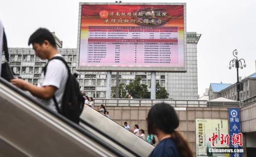 资料图:2017年8月23日,济南火车站广场大屏幕24小时循环播放失信被执行人信息,引得许多旅客驻足观看。 中新社记者 张勇 摄