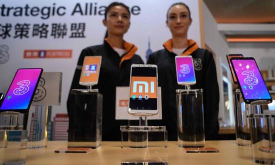 图示:小米在新闻发布会上展示自家手机,并宣布与英国电信服务运营商Three达成合作