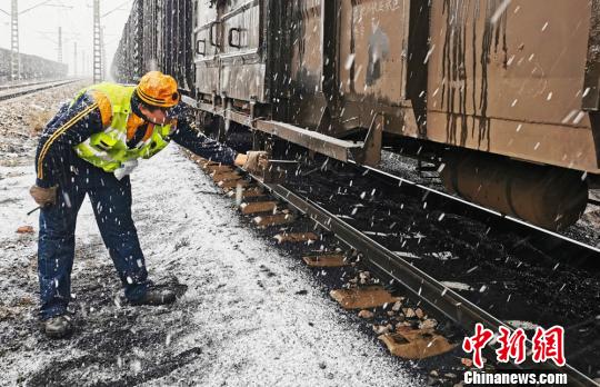 图为铁路工人正在检查相关设备运行情况，确保冰雪天气铁路运输安全平稳。　王光辉 摄