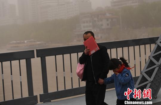 图为一对父女在风沙中出行。 杨艳敏 摄 沙尘暴侵袭兰州 黄河“水天一色”