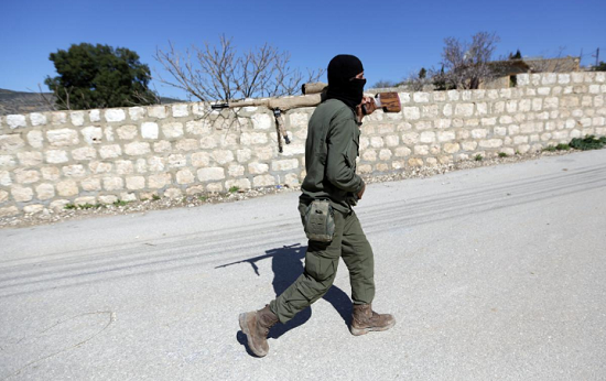 2018年3月17日，一名土耳其支持的叙利亚自由军战士在叙利亚阿夫林地区持武器向北行进。（图源：路透社）