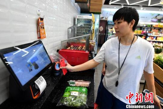 图为陈燕亭在福州一家无人超市内购物并用支付宝自助结账。大陆的“无现金”支付、共享经济等让她颇感新鲜,她笑说回台湾常常忘带钱包上街,准备付账才恍然大悟。 吕明 摄