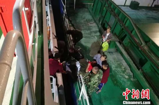  救援人员协助船员将病人转移到海巡艇上。　王黎　摄