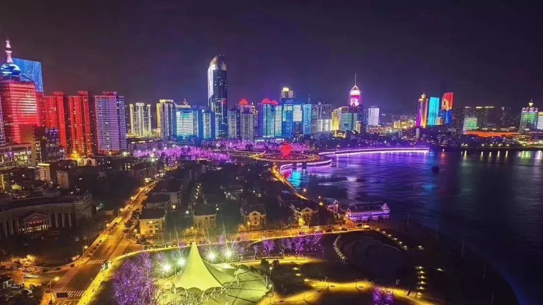 先来一段航拍视频(视频来源:King) 新华网曾评选国内最美十大夜景城市, 青岛荣登榜单前十位。 五彩缤纷的灯光下, 闪动着青岛的过去、现在与未来, 千番图景,万种风情。 红瓦绿树碧海蓝天在夜幕下隐去色彩,呈现出另外一番景致。青岛湾和团岛湾璀璨的夜色令人陶醉。 雪夜迎宾馆。灯光和白雪洒落在老建筑上,悠悠诉说着历史与未来。 夜色中的跨海大桥,似一条长龙横跨海上。这是城市交通的一大步,也是美的跨越! 东方影都大剧院,点缀在海螺上的射灯,像夜幕中滑落的点点繁星,犹如梦境。 漫步李村河上