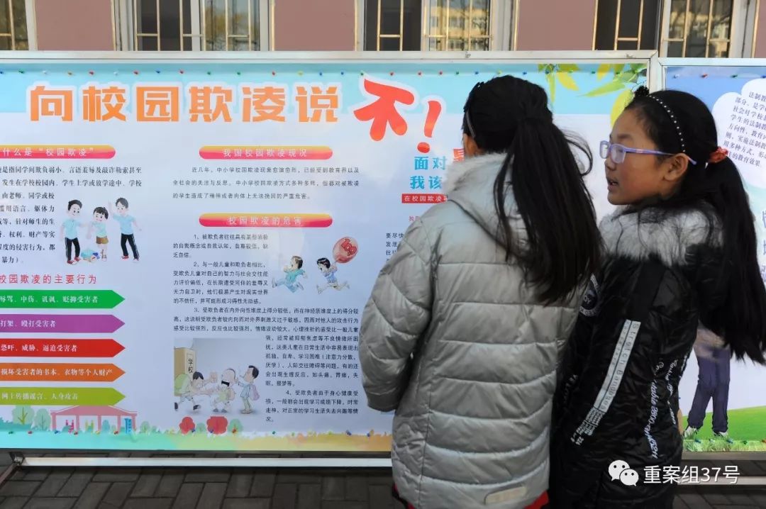 2017年11月23日,青岛广饶路小学的学生在操场上学习“向校园欺凌说不”法制教育宣传图版。图片据视觉中国