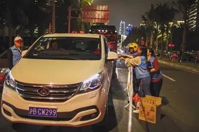 ▲21日晚,海口秀英港附近,志愿者一直忙碌着为滞留旅客送水送饭,不时有滞留旅客前来感谢。图/视觉中国