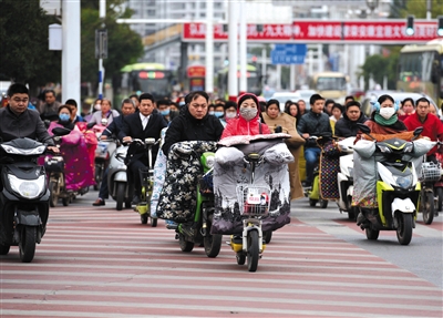 2017年10月23日，江苏省淮安市街头，市民骑乘电动车通过路口。图/视觉中国