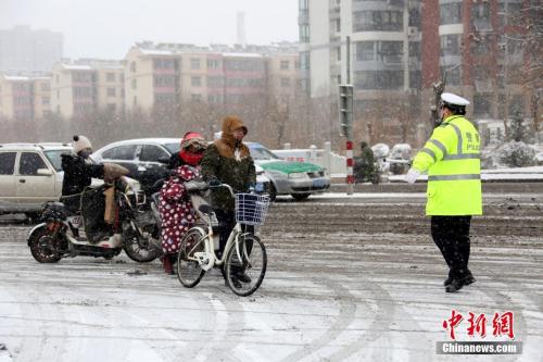  1月4日，山东省枣庄市公安局市中分局交通警察大队民警在当地的西外环路上冒雪指挥交通。 中新社发 吉 喆 摄 图片来源：CNSPHOTO