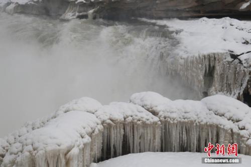 陕西延安黄河壶口瀑布一片银装素裹,瀑布两岸被积雪覆盖,岩石和护栏上出现大小不一、形态各异的冰挂,积雪和冰挂让冬日里的壶口瀑布更显辽阔与壮观。梁鹏 摄 陕西延安黄河壶口瀑布一片银装素裹,瀑布两岸被积雪覆盖。梁鹏 摄