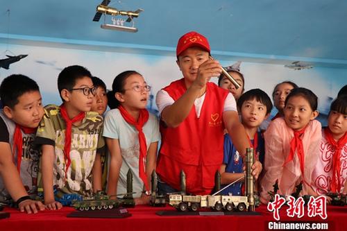 资料图:志愿者在给小学生讲解各军事装备模型。中新社记者 张娅子 摄