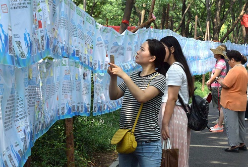 资料图:一名市民在济南千佛山公园举行的“七月七相亲大会”上用手机记录相亲信息。新华社记者 徐速绘 摄