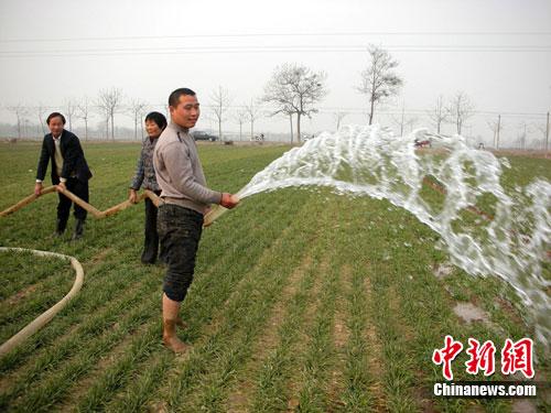 资料图：农民在田间浇麦抗旱。