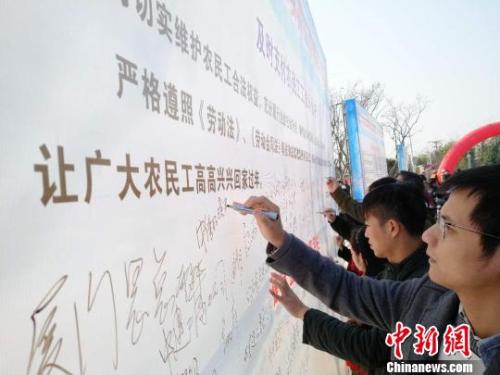 资料图：企业代表在背景墙签署《及时支付农民工工资承诺书》。王剑 摄